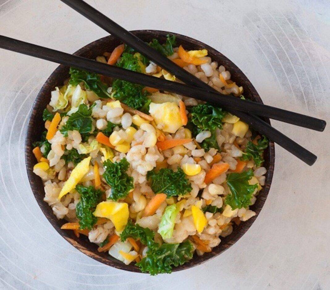 Bowl of fried rice with vegetables with chop sticks