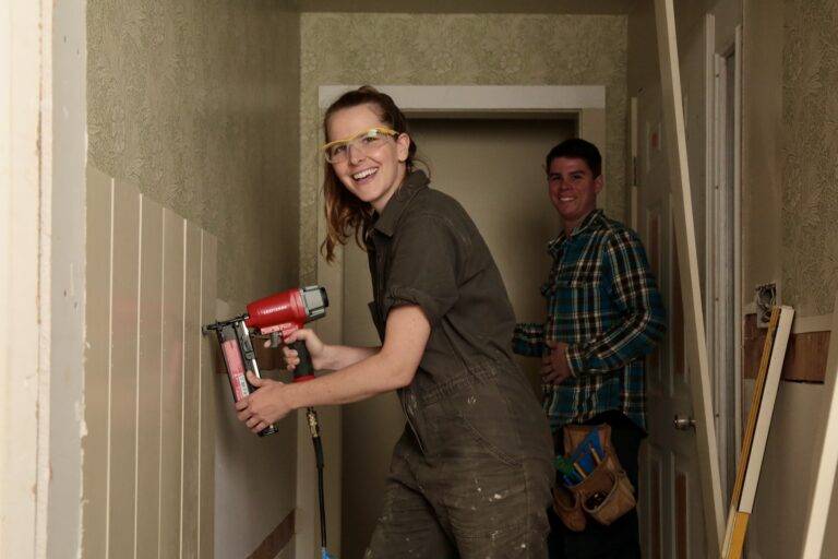 Bea smiles to camera while installing wainscoting in entryway.