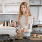 Cleo is in the Bluedot Kitchen adding grated pears to a bowl with her cake batter.